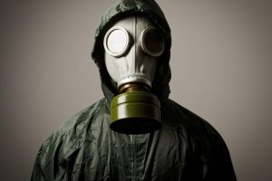 A man in a black hoodie wearing gas mask.